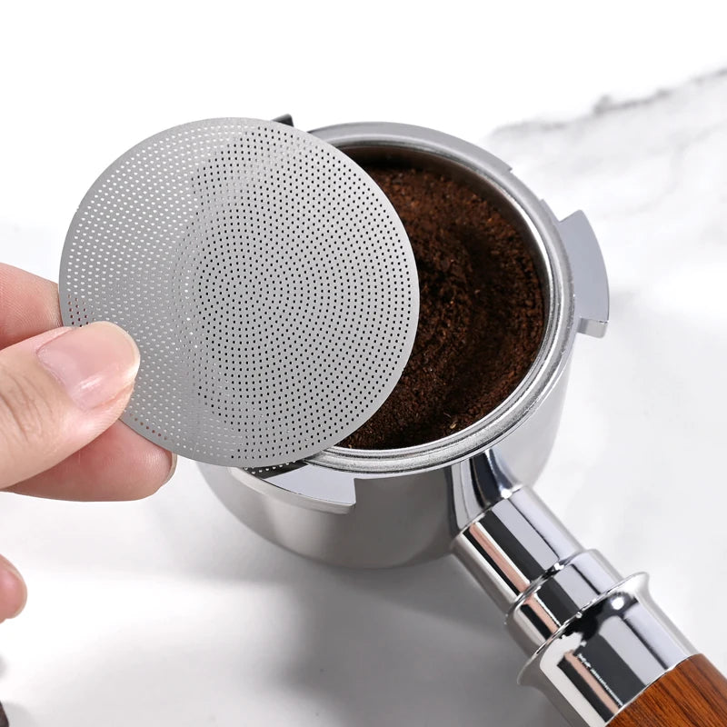 Hand placing espresso puck screen over portafilter with fresh coffee grounds