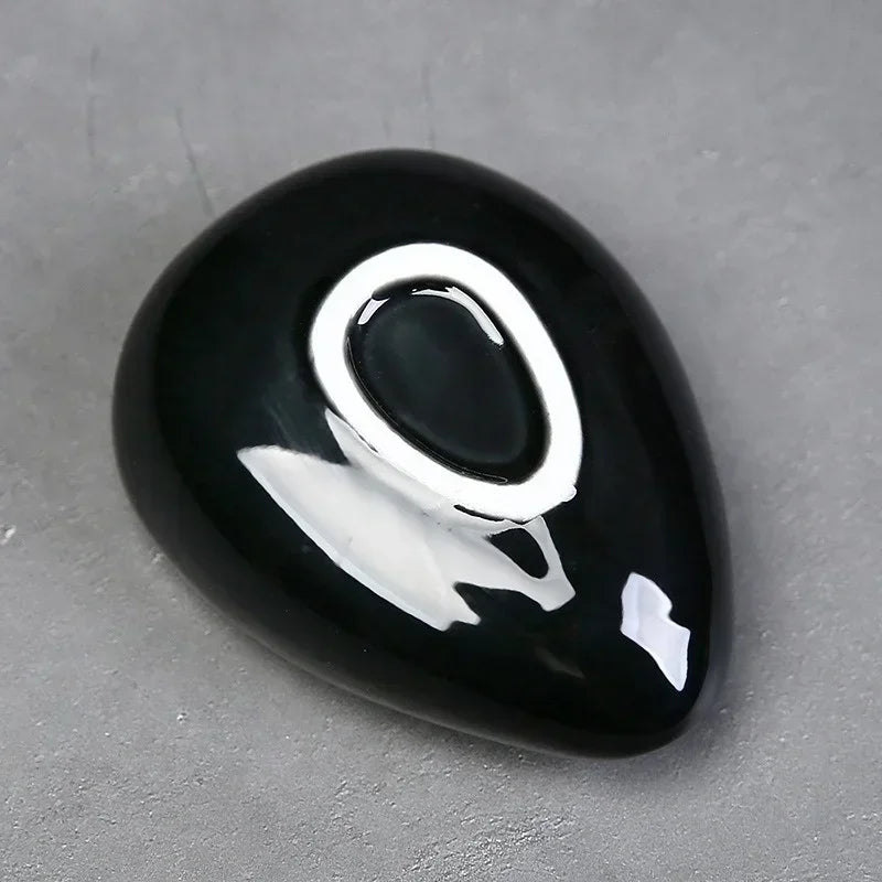 Polished black onyx stone with glossy finish on a gray surface
