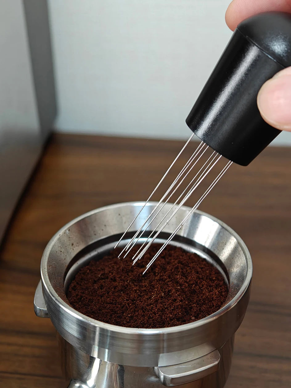 Espresso distribution tool leveling ground coffee in portafilter on wooden counter