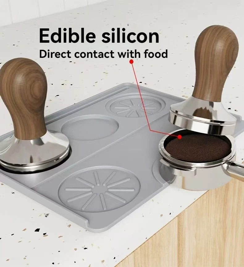 Espresso tamping mat made of food-safe silicone with wooden handle tampers on kitchen counter.