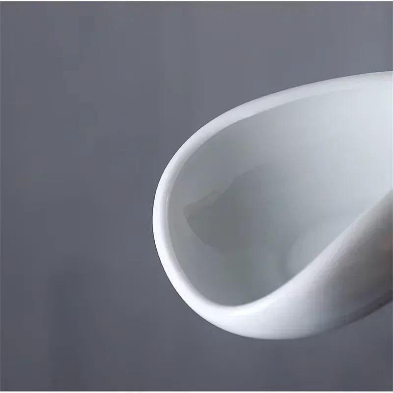 Closeup of a white ceramic coffee cup with a modern, minimalist design on a grey background