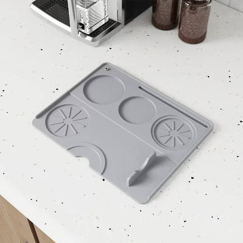 Gray silicone espresso tamping mat on a white kitchen counter near espresso machine