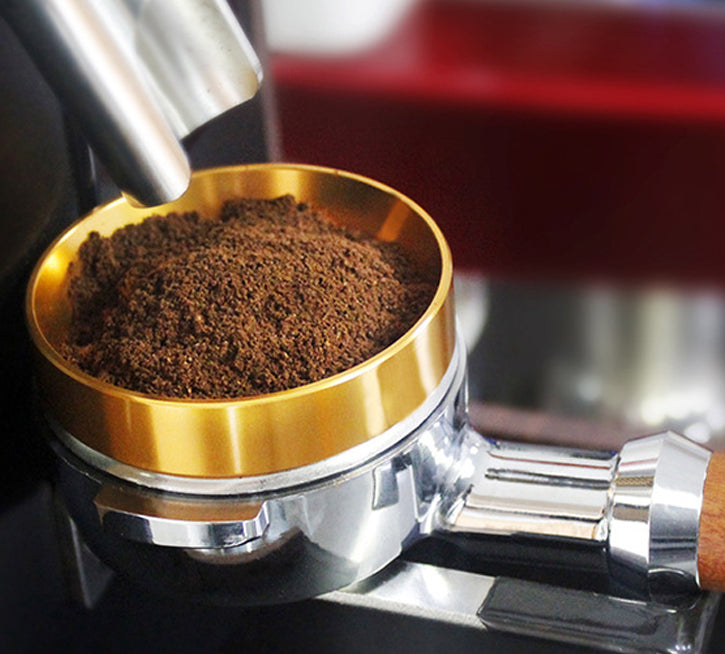 Espresso portafilter with gold dosing ring filled with fresh ground coffee