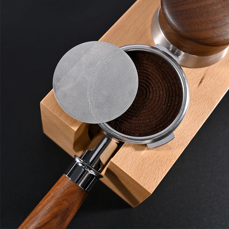 Espresso portafilter with puck screen, fresh coffee grounds, wooden handle and tamper