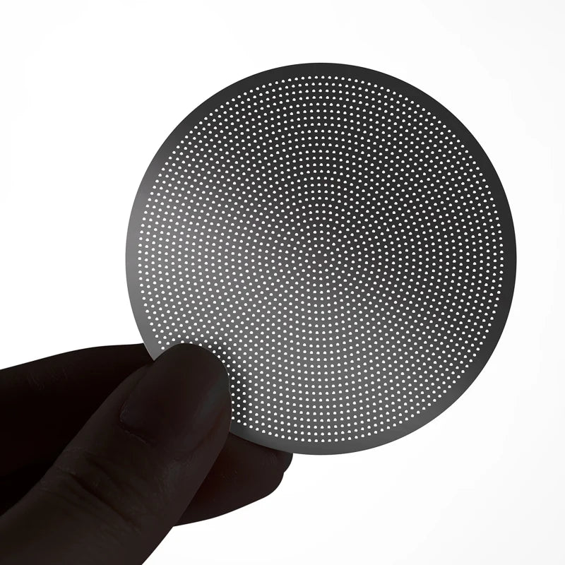 Hand holding a stainless steel espresso puck screen for coffee extraction